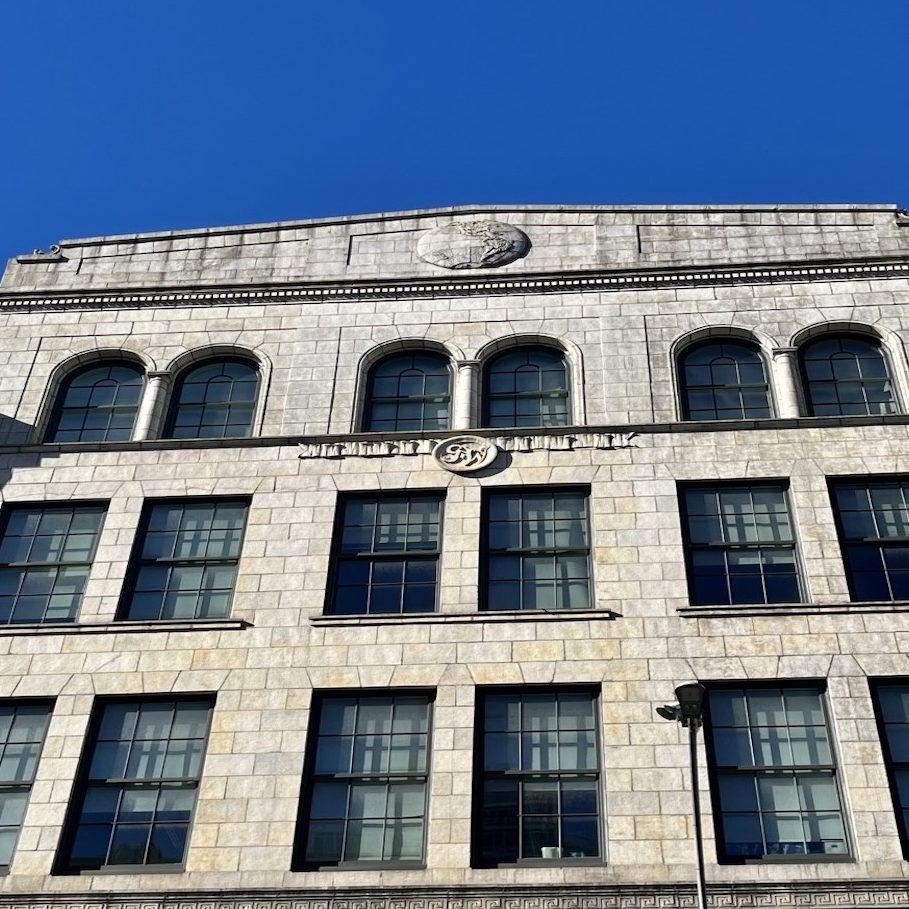 Photo of the former Globe Wernicke building at 451 Broadway, featuring a logo embellished with the initials "G-W" and a decorative globe at the top of the building.